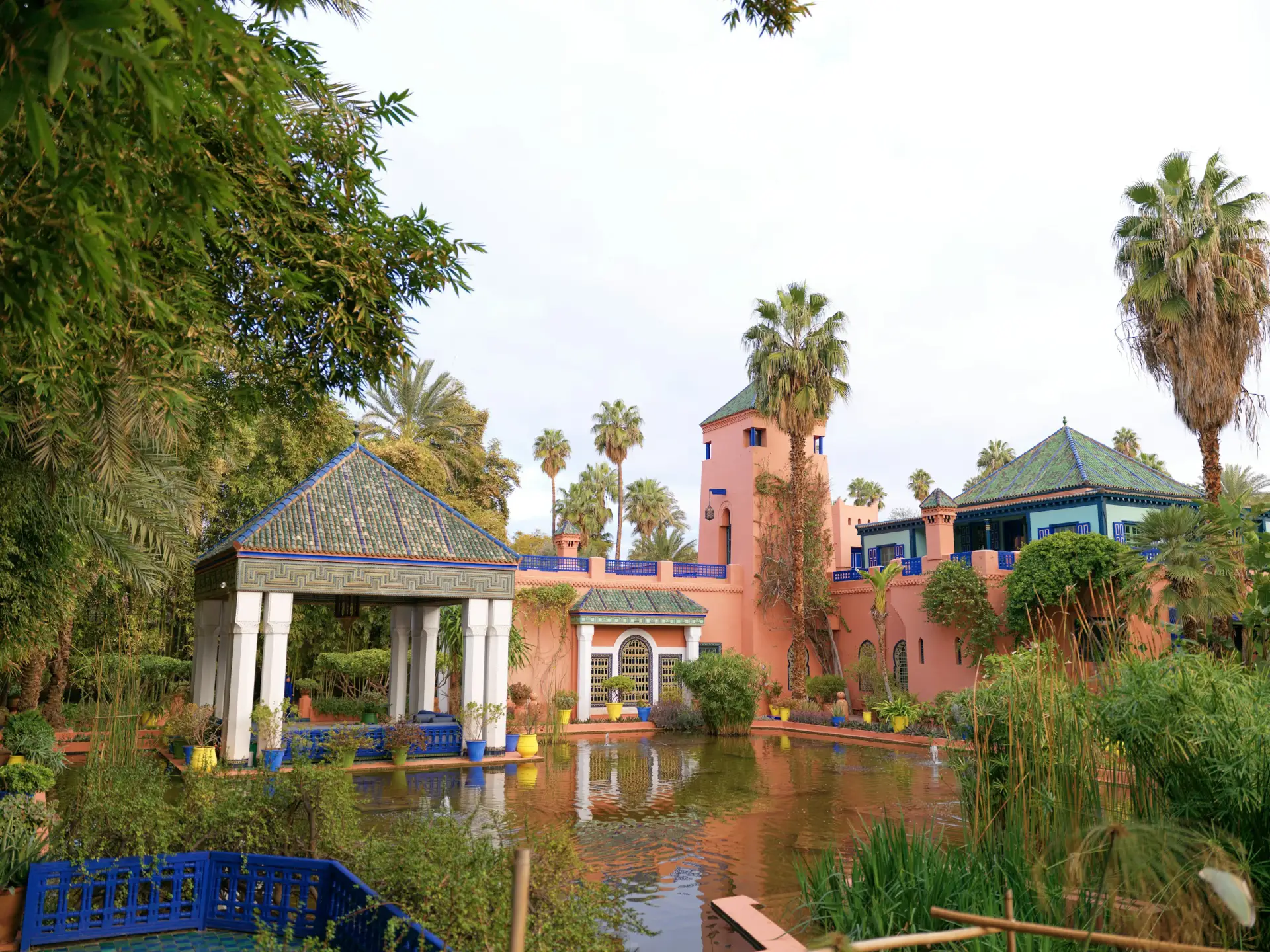 Pavillon, bassin et palmiers devant une demeure ocre de Marrakech